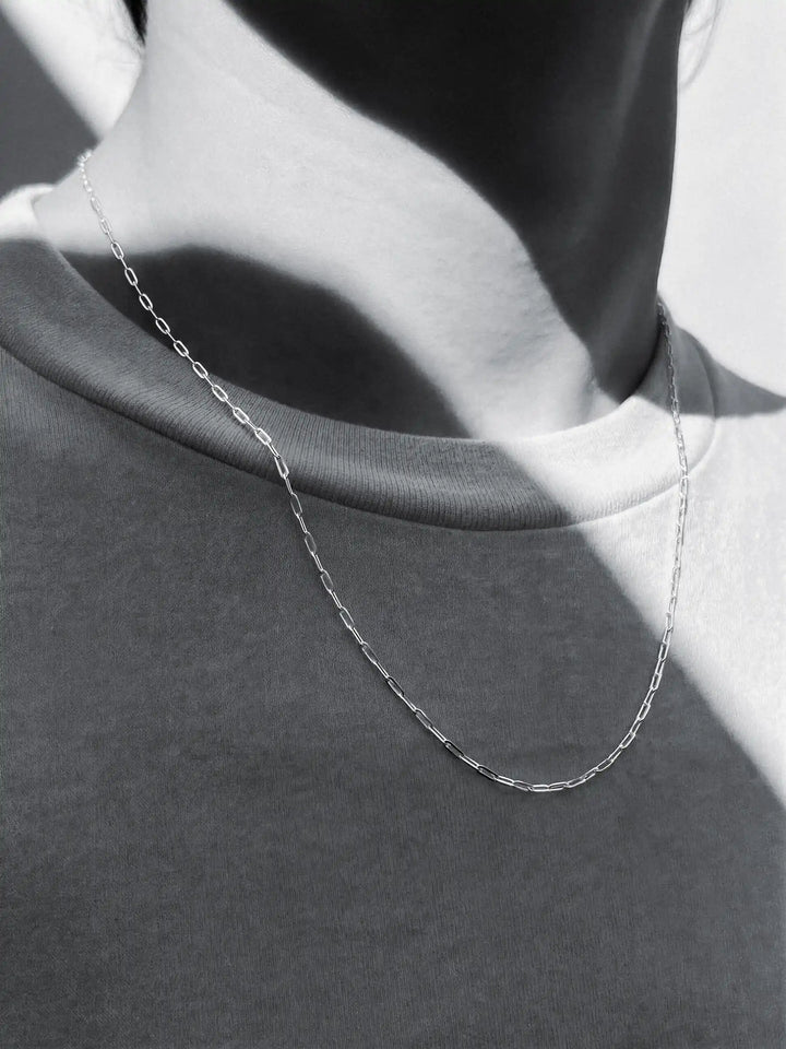 Silver chain necklace on a person with a plain background
