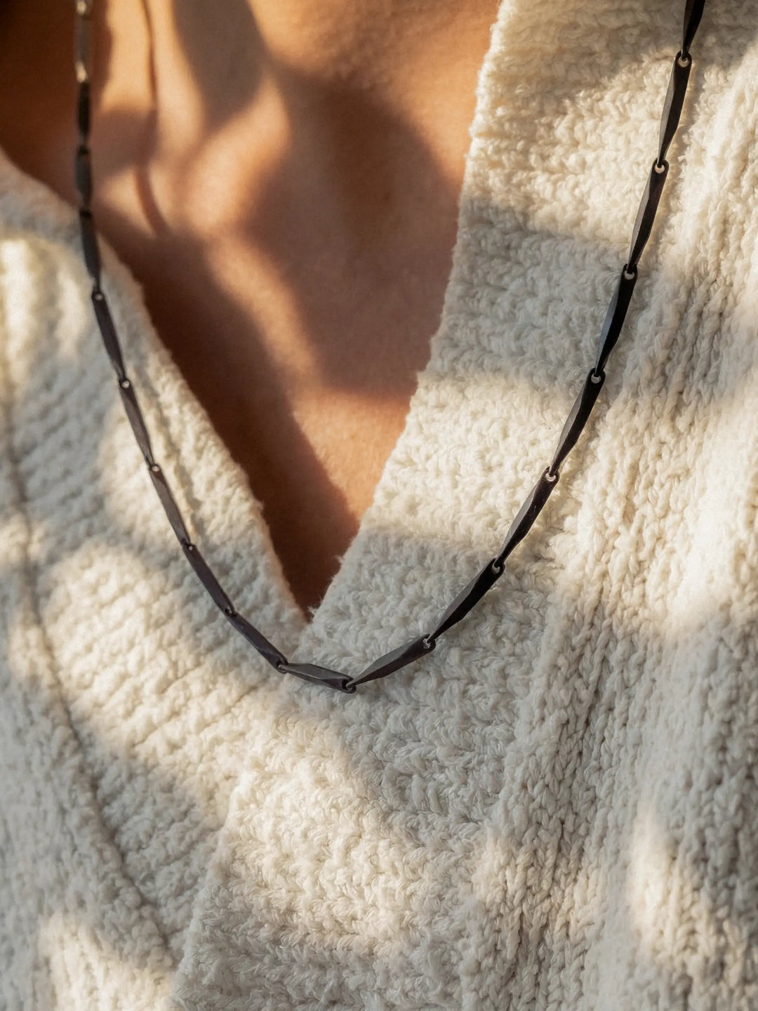 Close-up of a black necklace around a person's neck