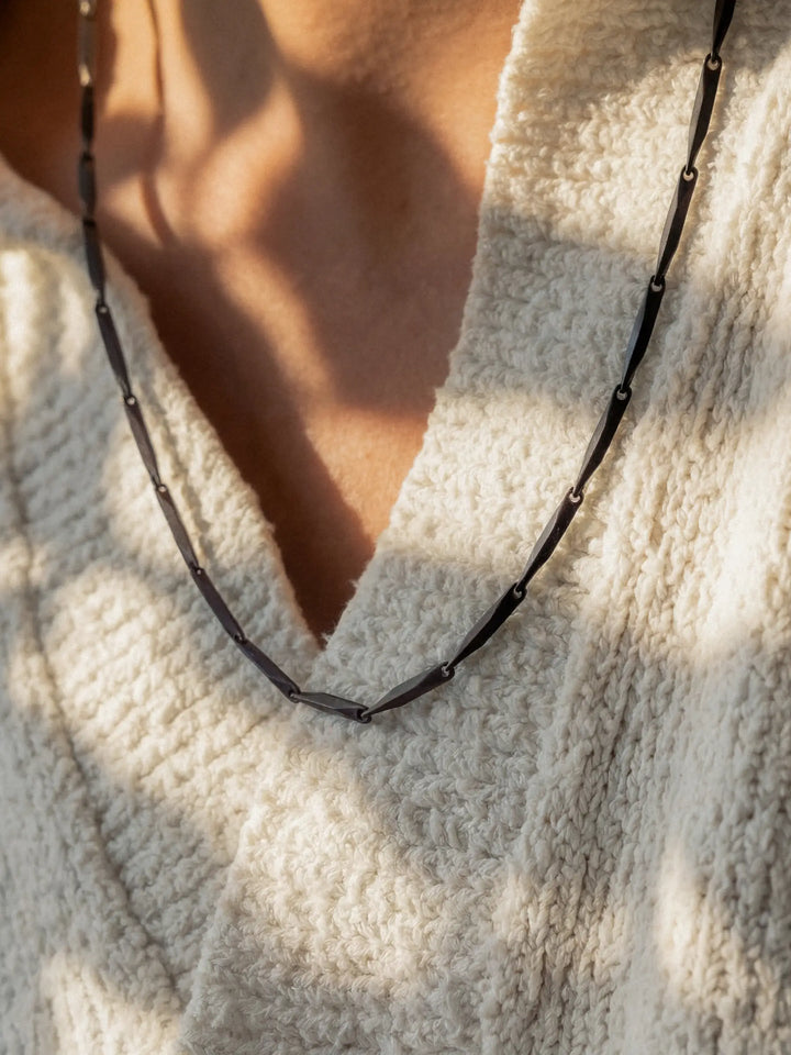 Close-up of a black necklace around a person's neck
