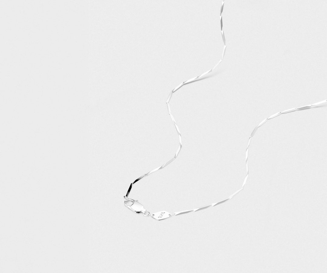 Silver necklace on a light-gray background