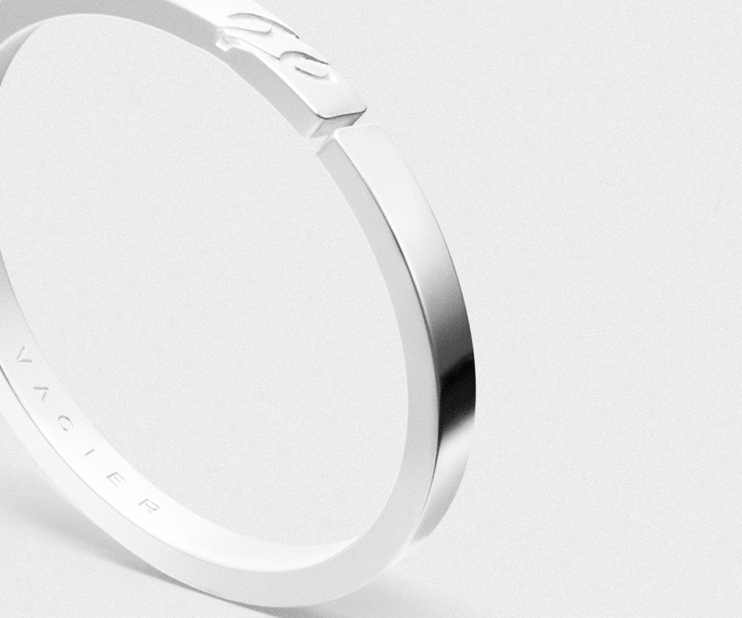 Close-up of a silver ring with 'Vacier' engraving on a light gray background