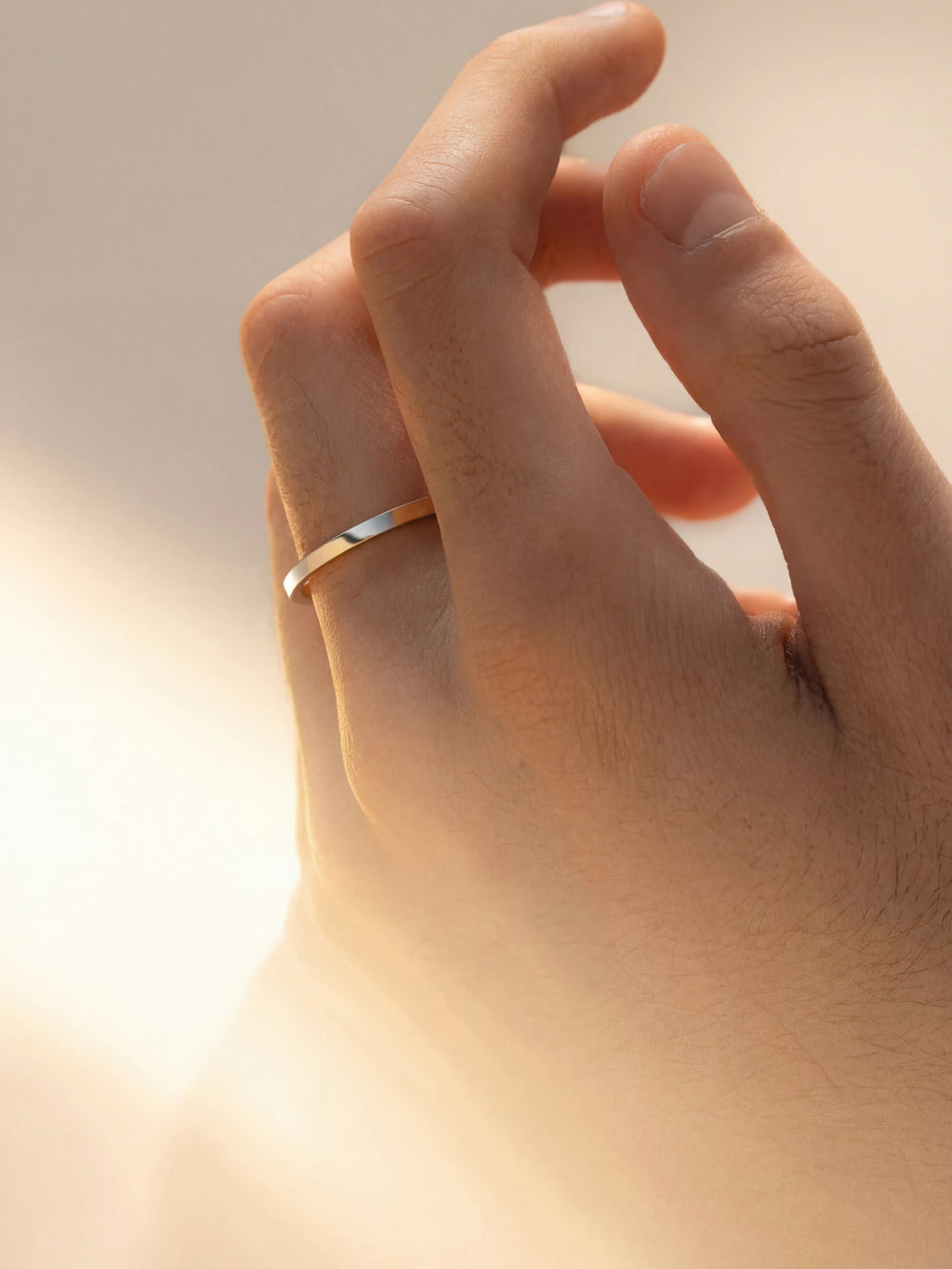 Hand wearing a gold ring with a soft focus background