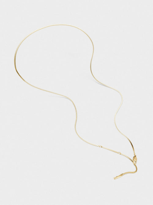 Gold necklace on a light gray background