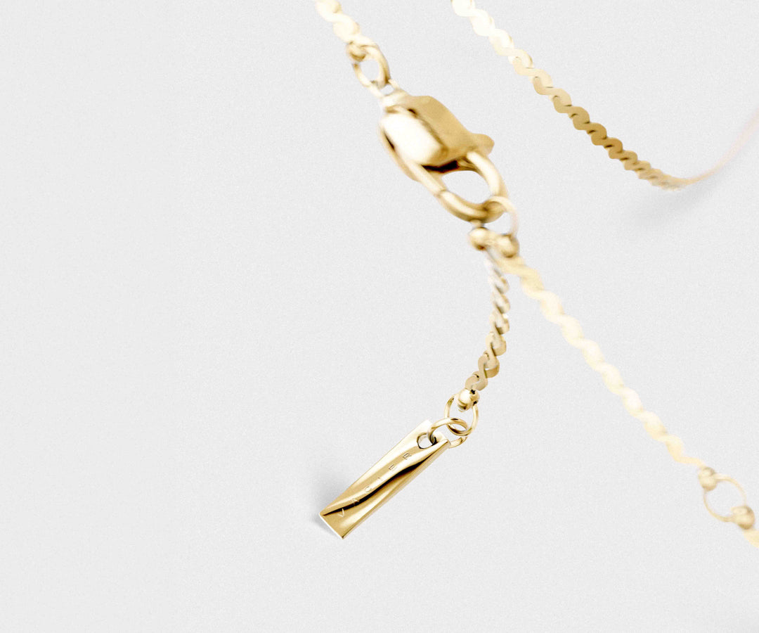 Close-up of a gold bracelet with a clasp on a light gray background