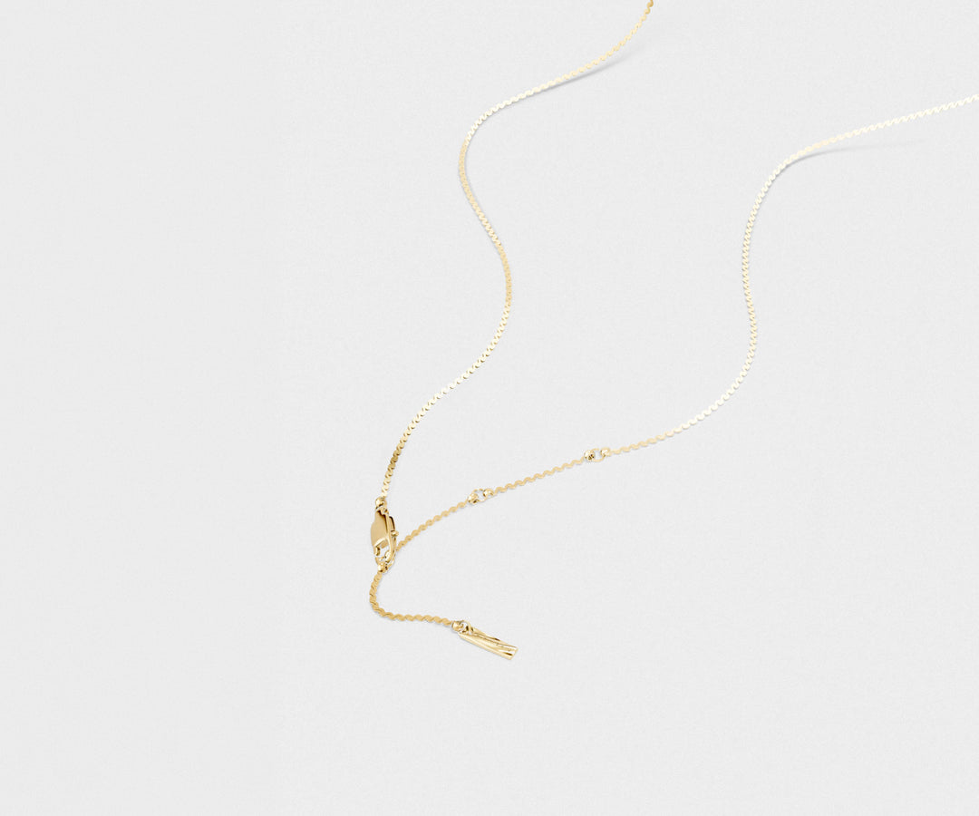 Close-up of a gold necklace on a light gray background