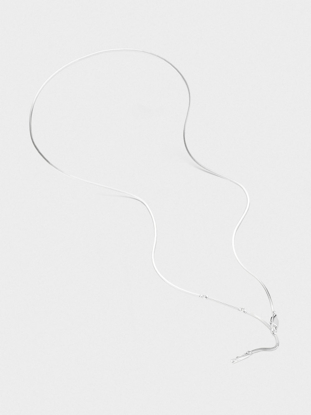 Silver necklace on a light gray background